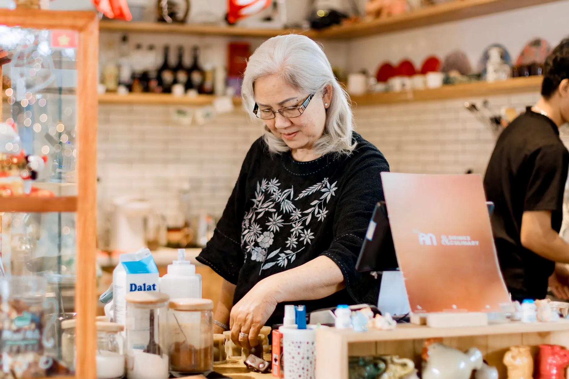 A cafe owner smiling behind the counter